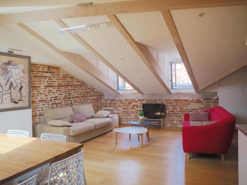 a living room with a red couch and a brick wall at Les Toits du Capitole - Loft de standing 60 m2 - Parking en option in Toulouse