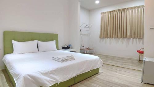 a bedroom with a large bed with a green headboard at NO.14 in Tainan