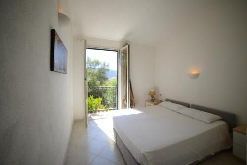 a bedroom with a white bed and a large window at Villaggio Sa Ventana in Badesi