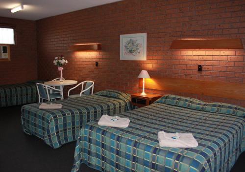 a hotel room with two beds and a table with chairs at Melaleuca Lodge Beaconsfield in Beaconsfield