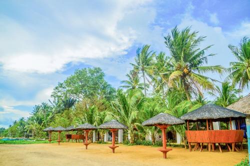 a group of tables and umbrellas on a beach at Camaya-an Paradise Beach Resort in Malabugas