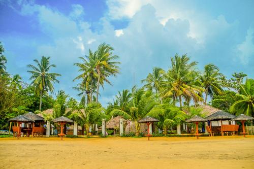 a row of houses on a beach with palm trees at Camaya-an Paradise Beach Resort in Malabugas