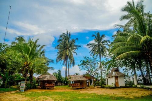 a group of huts and palm trees on a field at Camaya-an Paradise Beach Resort in Malabugas