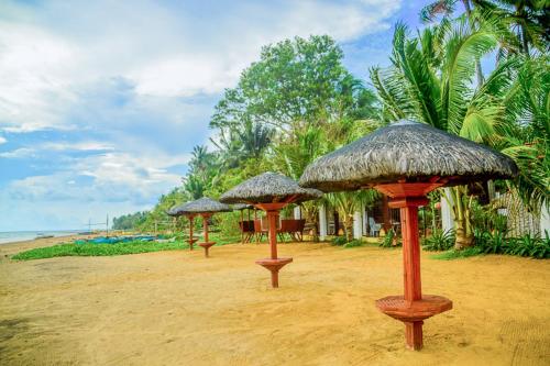three umbrellas sitting on a beach with the ocean at Camaya-an Paradise Beach Resort in Malabugas