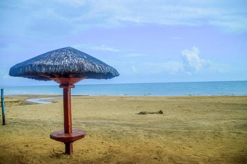 a straw umbrella sitting on a beach near the ocean at Camaya-an Paradise Beach Resort in Malabugas