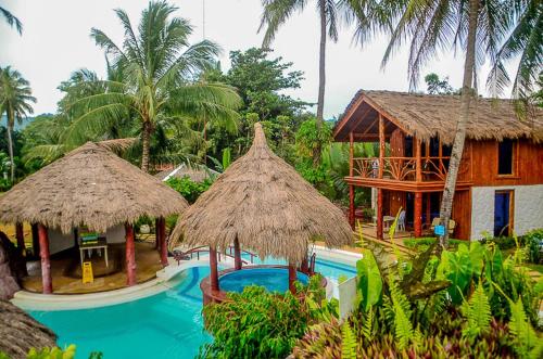 a resort with a swimming pool and a house at Camaya-an Paradise Beach Resort in Malabugas