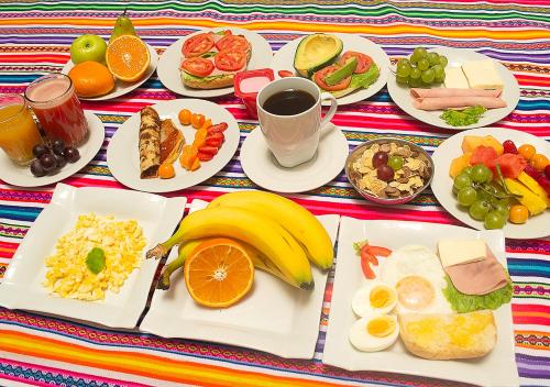 una mesa con platos de comida y bebida para el desayuno en Paypurix Hostel Lima Airport, en Lima