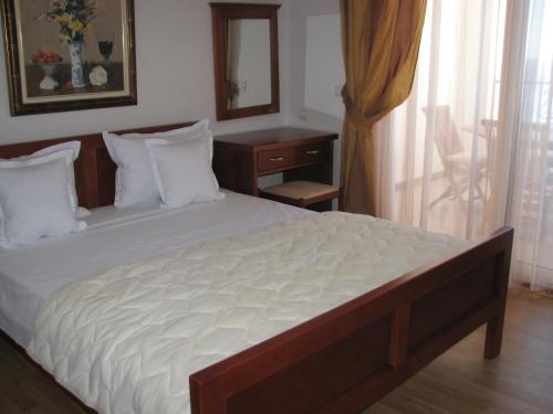 a bedroom with a large bed with a dresser and a mirror at Apartments Leut in Sveti Stefan