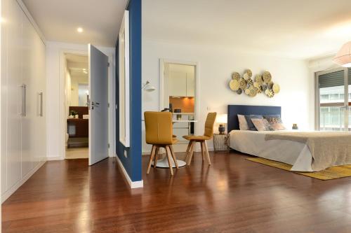 um quarto com uma cama, uma mesa e cadeiras em New loft with swimming pool at Parque das Nações! em Lisboa