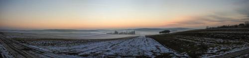 a snowy field with the sun setting in the background at Panoráma Üdülő in Aggtelek