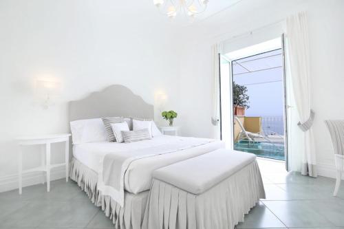 a white bedroom with a bed and a large window at Hotel Marincanto in Positano