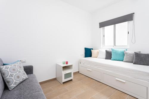 a white bedroom with a couch and a window at The wave house El Médano in El Médano