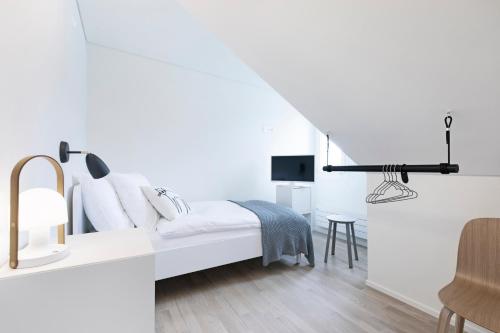 a white bedroom with a bed and a chair at Dom Studios in St. Gallen