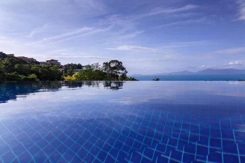 a large pool of water with trees and mountains in the background at villa Siam View Samui in Ban Bang Po