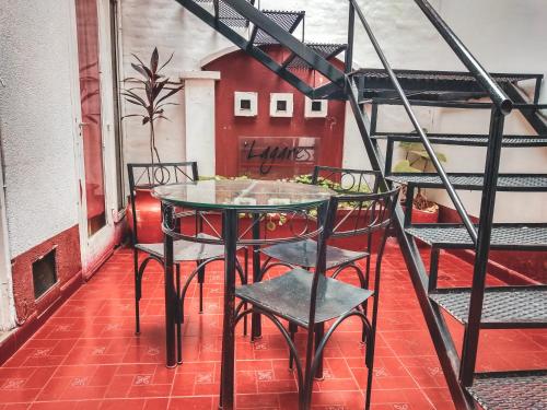 a glass table and chairs on a balcony at Hostel Lagares in Mendoza
