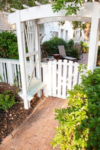 a white pergola with a bench next to a white fence at DeSoto Beach Gardens in Tybee Island