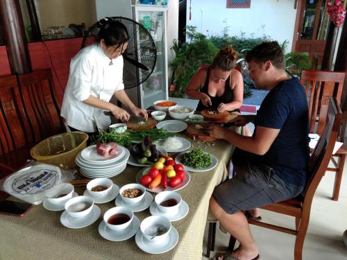 a group of people standing around a table with food at Herbal Tea Homestay in Hoi An