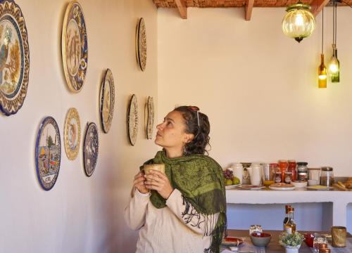 a woman standing in a kitchen with a cup of coffee at Hotel Pat'ta Hoiri in San Pedro de Atacama