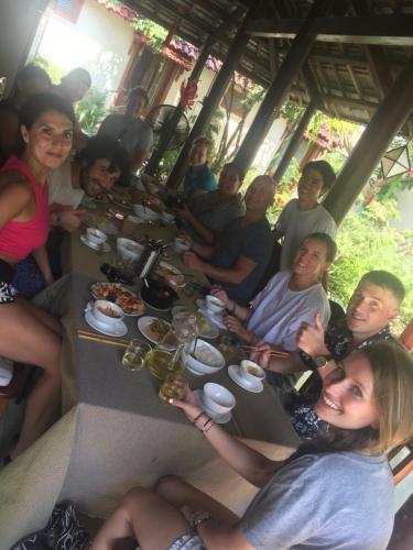 a group of people sitting around a table eating food at Herbal Tea Homestay in Hoi An