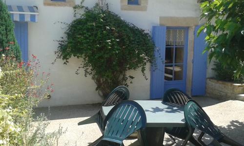 a table and chairs in front of a house with a blue door at LA MAISON BLEUE in Saint-Gelais
