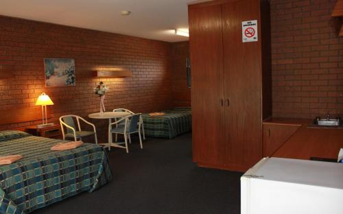 a hotel room with two beds and a table with chairs at Melaleuca Lodge Beaconsfield in Beaconsfield