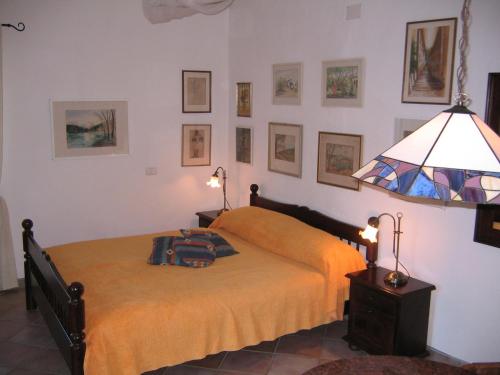 a bedroom with a bed and a lamp and pictures on the wall at Studio-Appartment in Landhaus mit Meerblick in Porto Azzurro