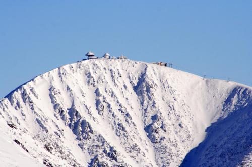 a snow covered mountain with people on top of it at Penzion V Kolonce in Strážné