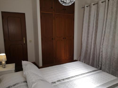 a bedroom with a bed with white sheets and a window at Nature Guesthouse in Lagos