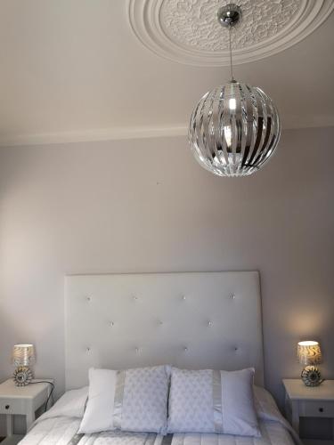 a white bedroom with a bed with a silver chandelier at Nature Guesthouse in Lagos