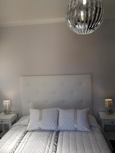 a bedroom with a white bed with a large headboard at Nature Guesthouse in Lagos