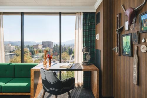 a living room with a table and a green couch at Graduate by Hilton Eugene in Eugene