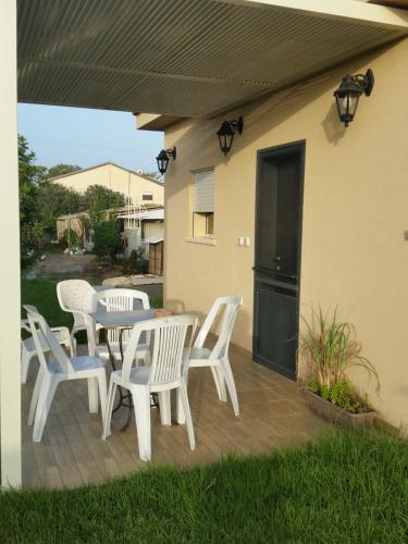 a patio with white chairs and a table and a building at Beit Haner Moshav Dor in Dor