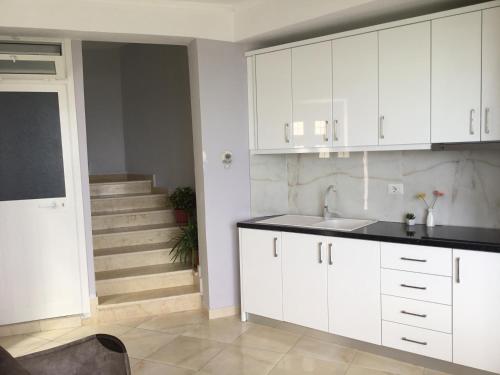eine Küche mit weißen Schränken, einem Waschbecken und einer Treppe in der Unterkunft Holiday Home Qeparo in Qeparo