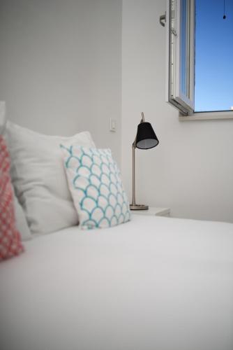 a white bed with a lamp on top of it at Apartments and Rooms Jospino in Mali Lošinj