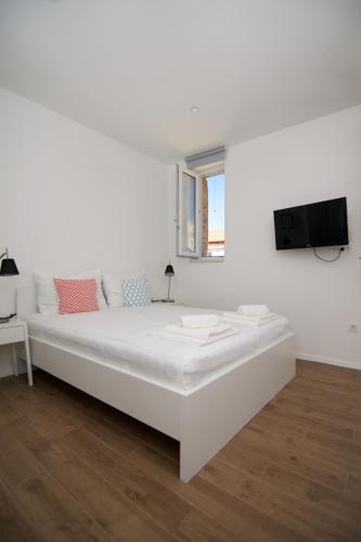a white bedroom with a large bed and a flat screen tv at Apartments and Rooms Jospino in Mali Lošinj