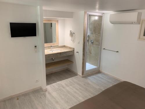 uma casa de banho com um chuveiro, um lavatório e uma televisão em Les Lauriers Roses em Rayol-Canadel-sur-Mer