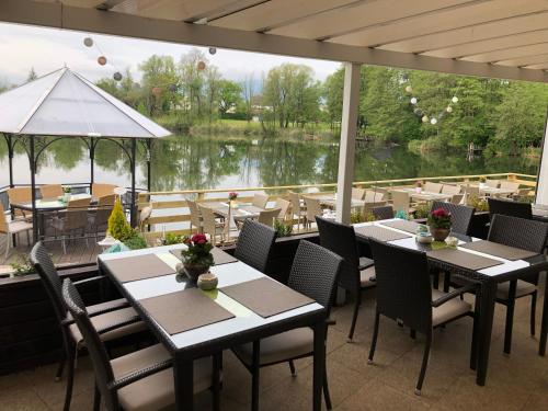 a restaurant with tables and chairs and a view of a lake at Hotel Seestuben in Villach