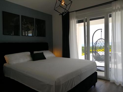 a bedroom with a white bed and a sliding glass door at Villa Orao in Kastel Novi