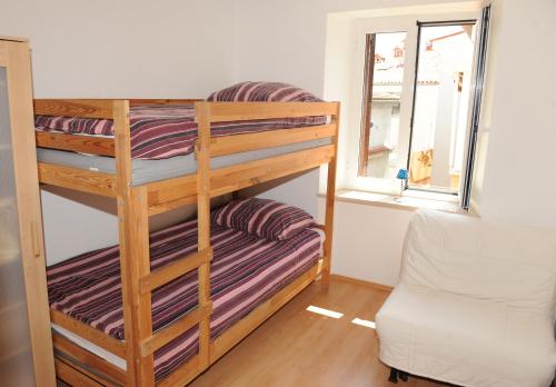 een stapelbed in een kamer met een bank en een raam bij Apartma LaVela in Izola