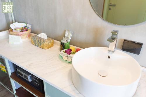 a bathroom with a white sink and a mirror at Samsen Street Hotel in Bangkok