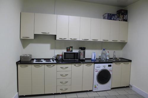 a kitchen with white cabinets and a washing machine at Park Hostel Osh in Osh
