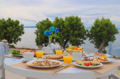 una mesa con platos de comida y bebidas. en Aeolos Bay Tinos en Tinos Town