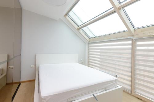 a bedroom with a white bed and a skylight at AMI Penthouse in Palanga
