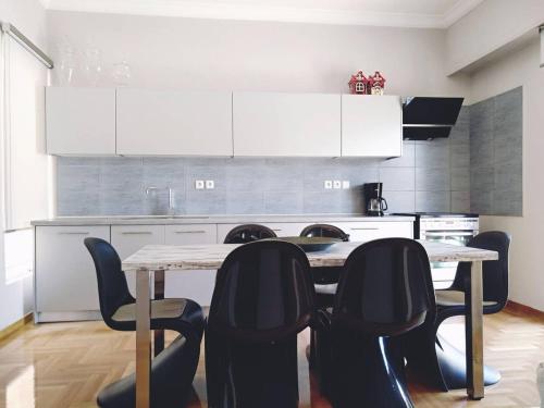 a kitchen with a table with chairs and white cabinets at The Athens Museum Penthouse 120sqm Lycabettus View in Athens