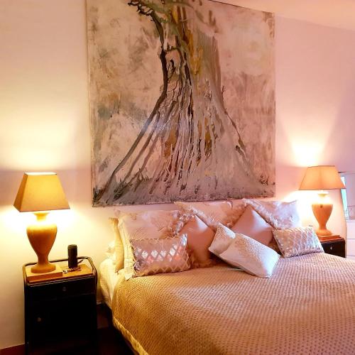 a bedroom with a bed with a painting above it at Las Fincas de Annie in Felanitx