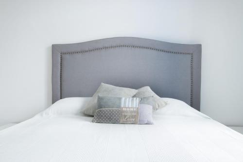 a white bed with a gray headboard and pillows at Poseidon Luxury Apartment in Karpathos Town