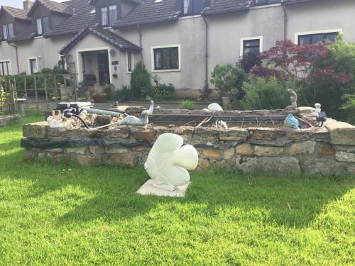 a statue in the grass in front of a house at Woodcockfaulds House in Stirling