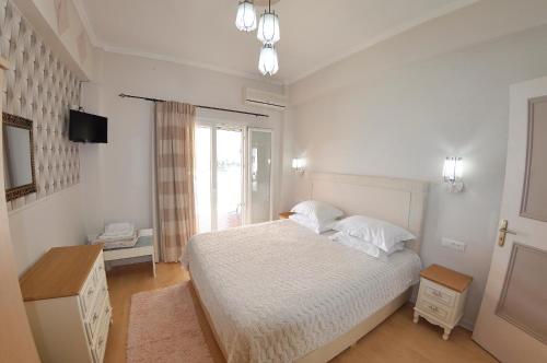 a white bedroom with a bed and a window at Tango Apartment On The Beach in Paleokastritsa