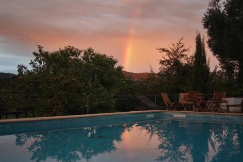 a pool with a rainbow in the background and a pool with a rainbow at Los Pozos de la Nieve in Constantina