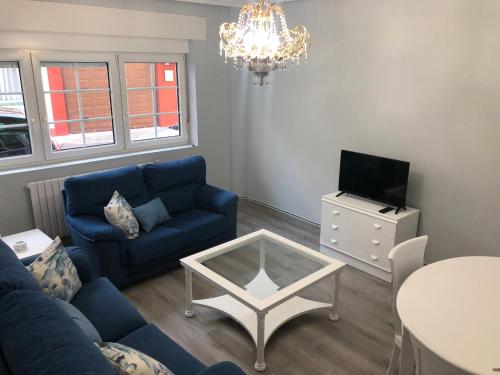 a living room with a blue couch and a table at Piso con vistas Fisterra in Fisterra